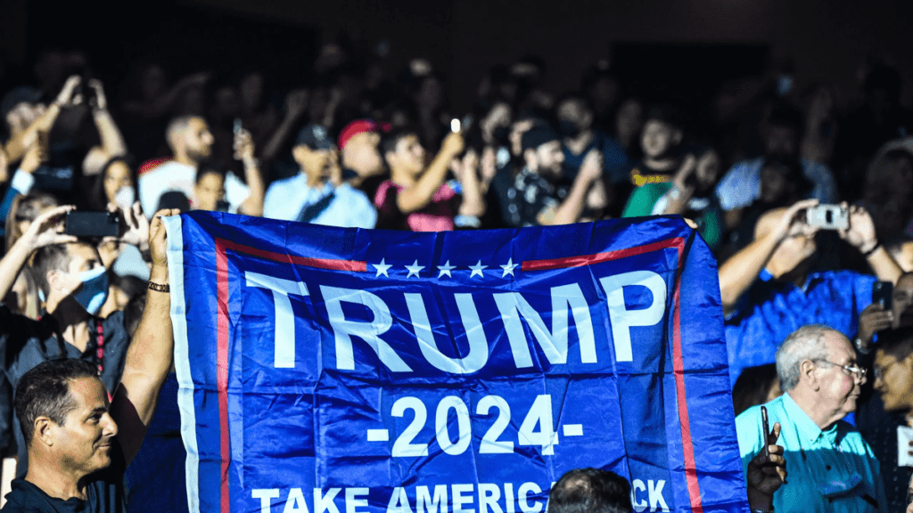 Des supporters de Donald Trump brandissant un drapeau “ TRUMP 2024 take America Back”