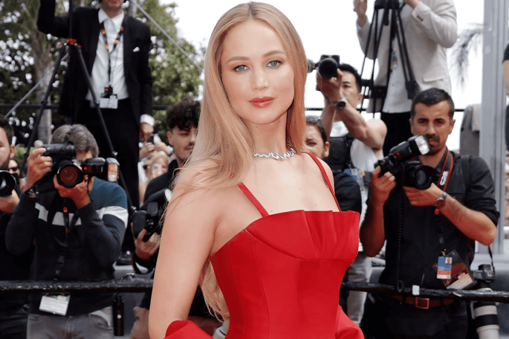 Jennifer Lawrence à Cannes entrain d’être prise en photo dans une robe rouge écarlate ce qui change de Jennifer Lawrence en tongs